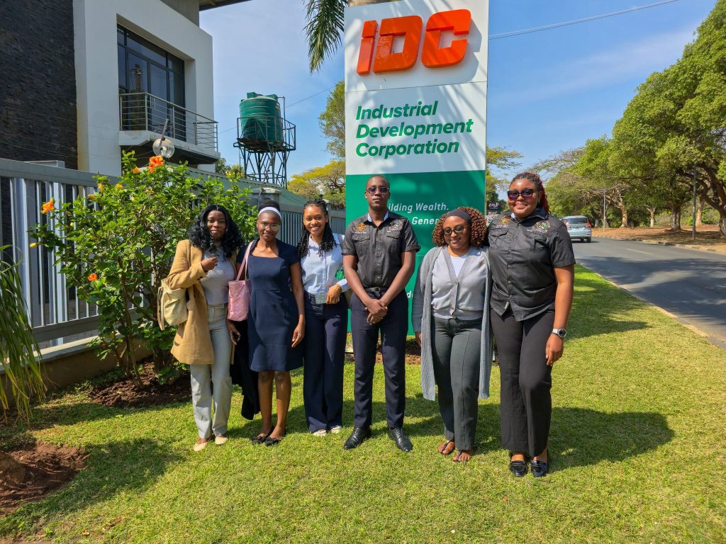 Members of the UNZADESA delegation stand beside the IDC sign at the Corporation’s Head Office.