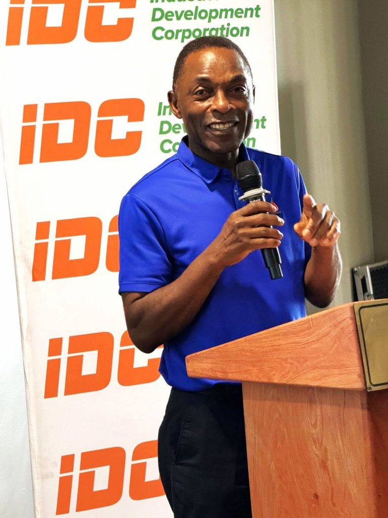 An IDC staff member in a blue polo shirt speaks at the podium during the conference.
