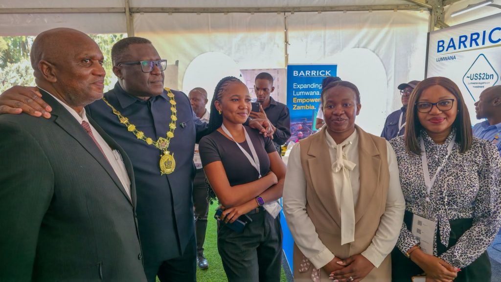 Delegates pose together at the Barrick exhibition stand during the conference.
