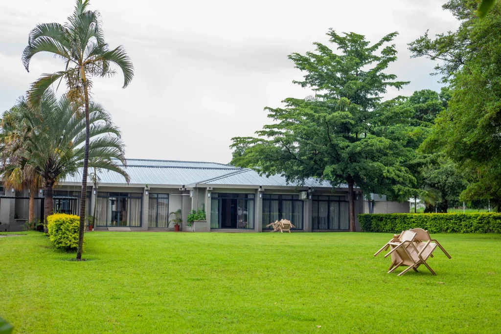 Mukuba Hotel buildings beside green lawns, palm trees and landscaped grounds.