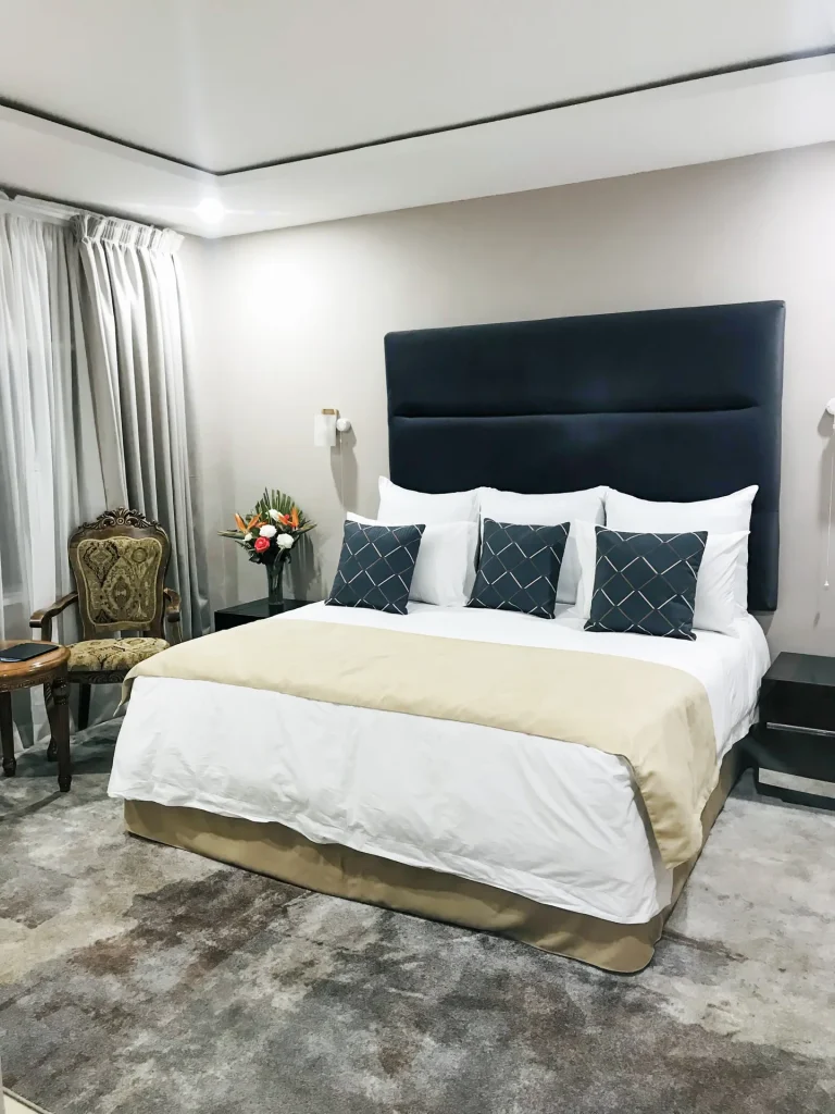 A refurbished Mukuba Hotel guest room with a double bed and upholstered headboard.